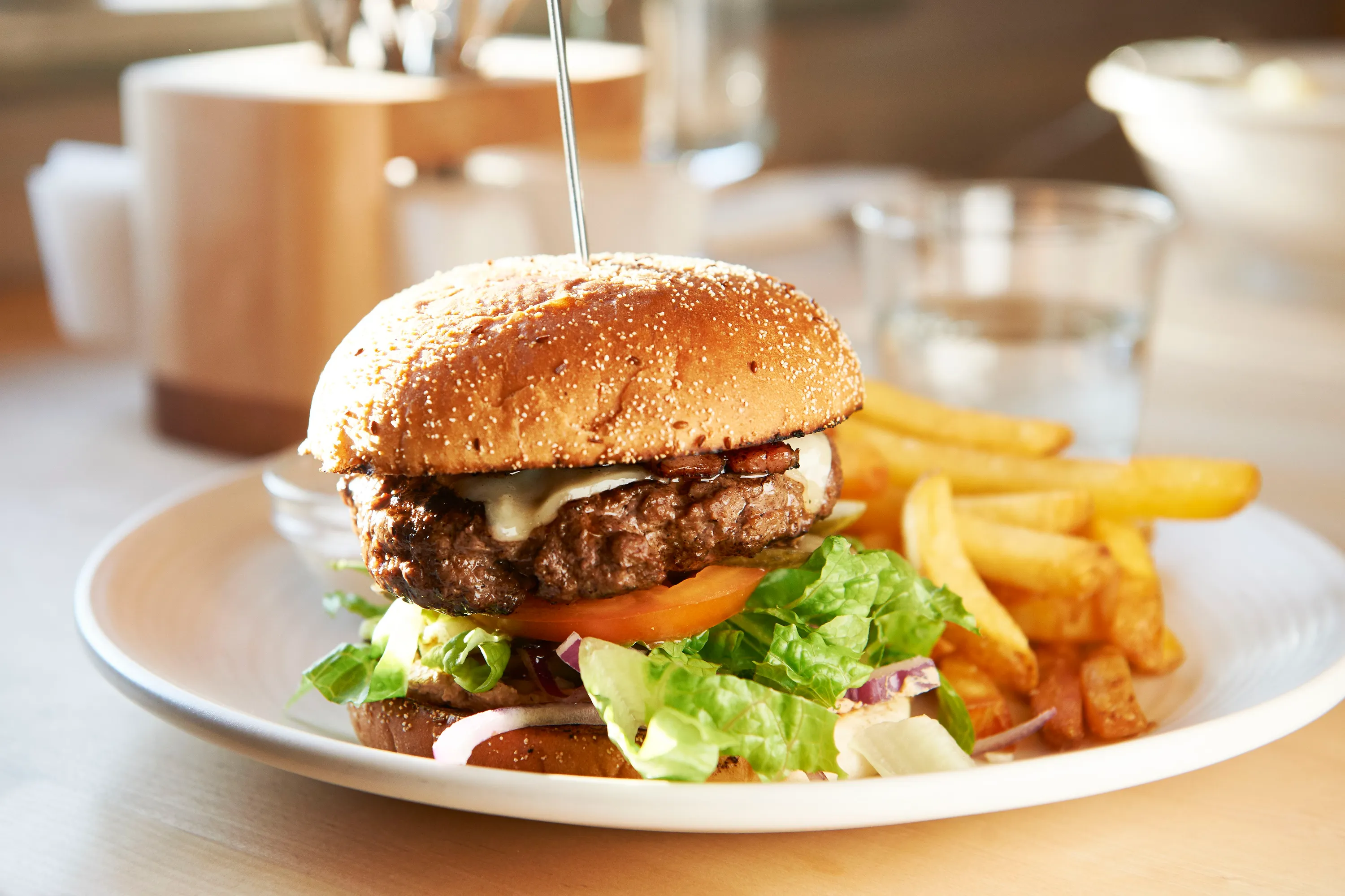 Tallrik med hamburgare med sallad, dressing och pommes.