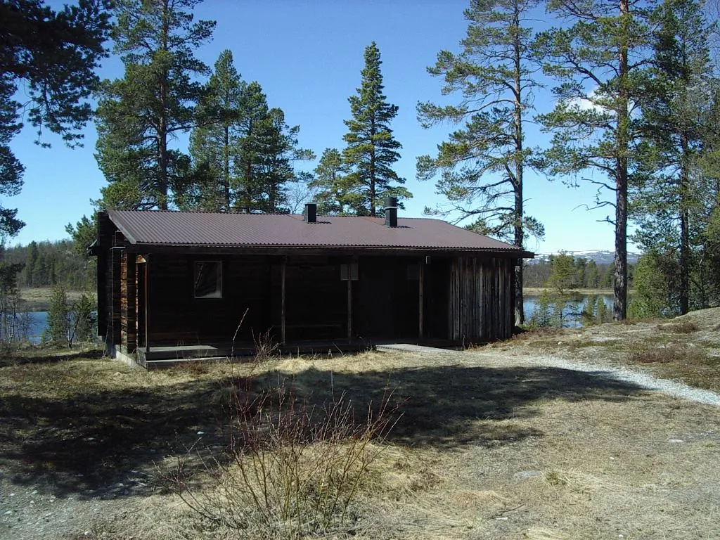 Stuga i skog, vid sjö.