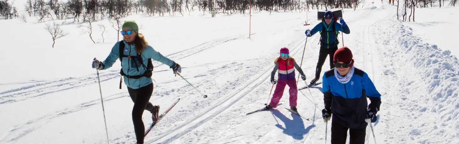 Familj är ute och åker längdskidor med sina barn