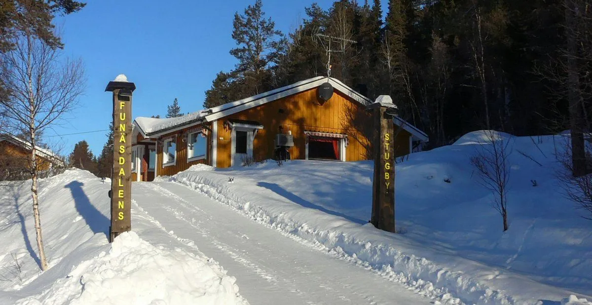 Infart till Funäsdalens stugby med gult hus i slutet på uppfarten.