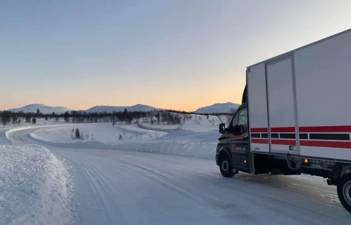 Lastbil på snöig fjällväg.