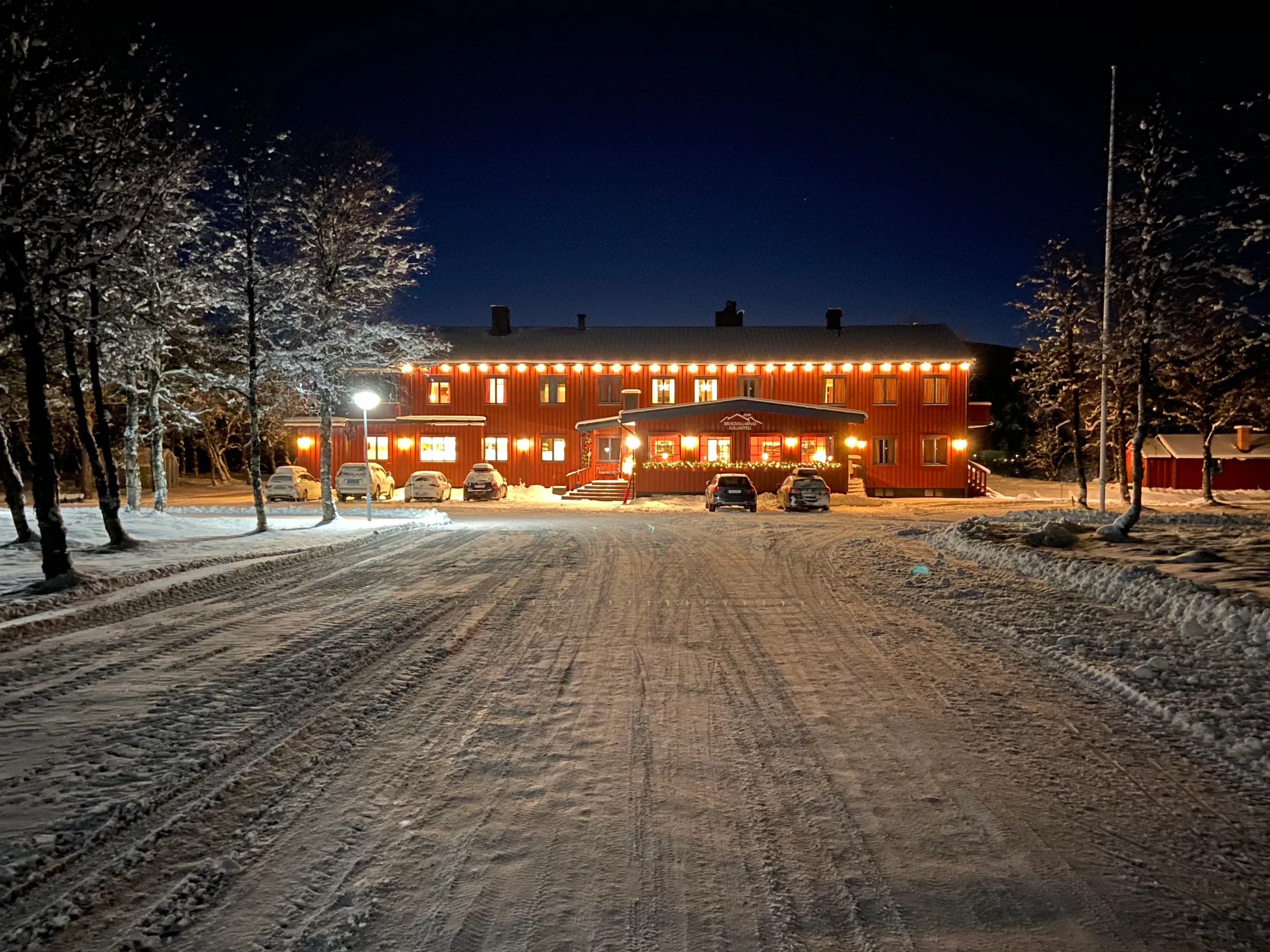 Bruksvallarnas Fjällhotell på kvällen, med belysning och snöig uppfart.
