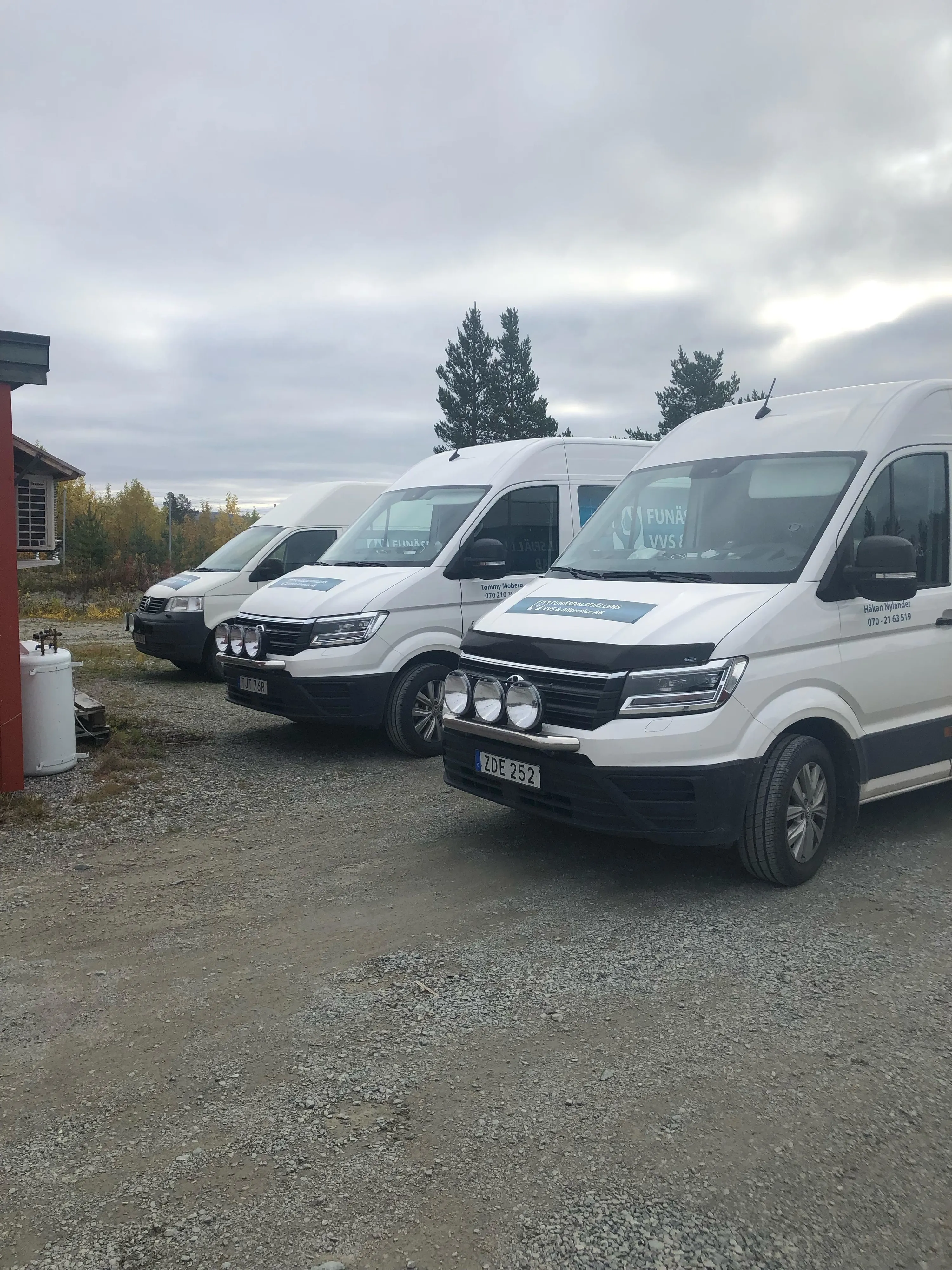 Tre skåpbilar på rad på parkering.
