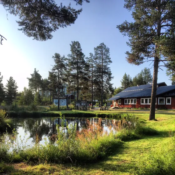 Liten damm med skog runt om och Tännäs Fiskecentrum i bakgrunden.