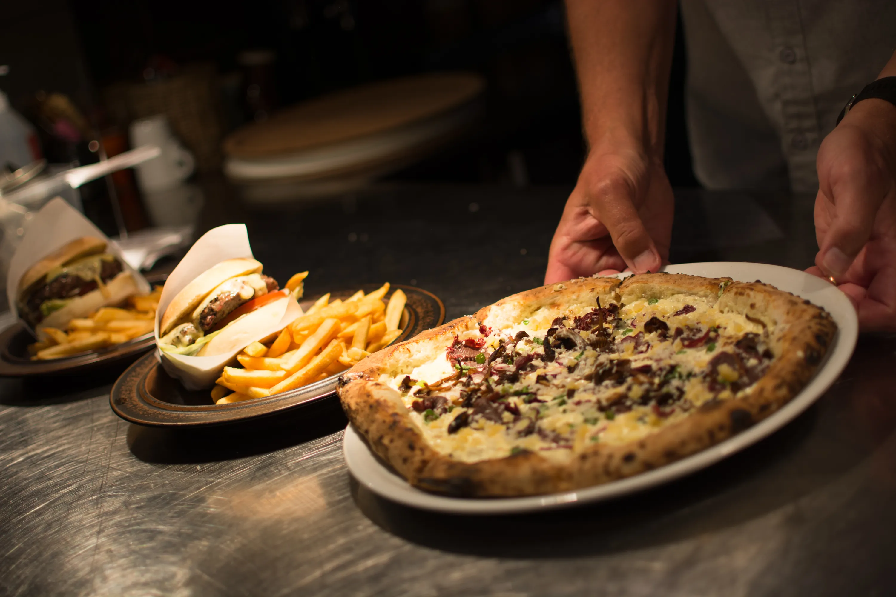 Tallrikar med pizza och hamburgare med pommes.