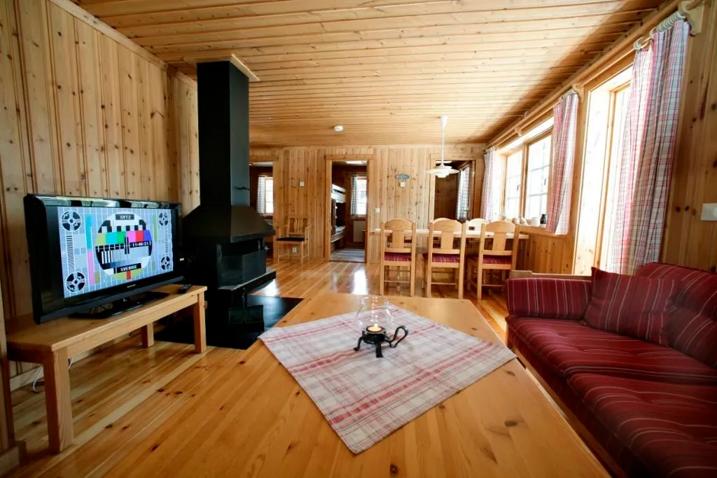 Stugmiljö med soffgrupp, braskamin och matplats.